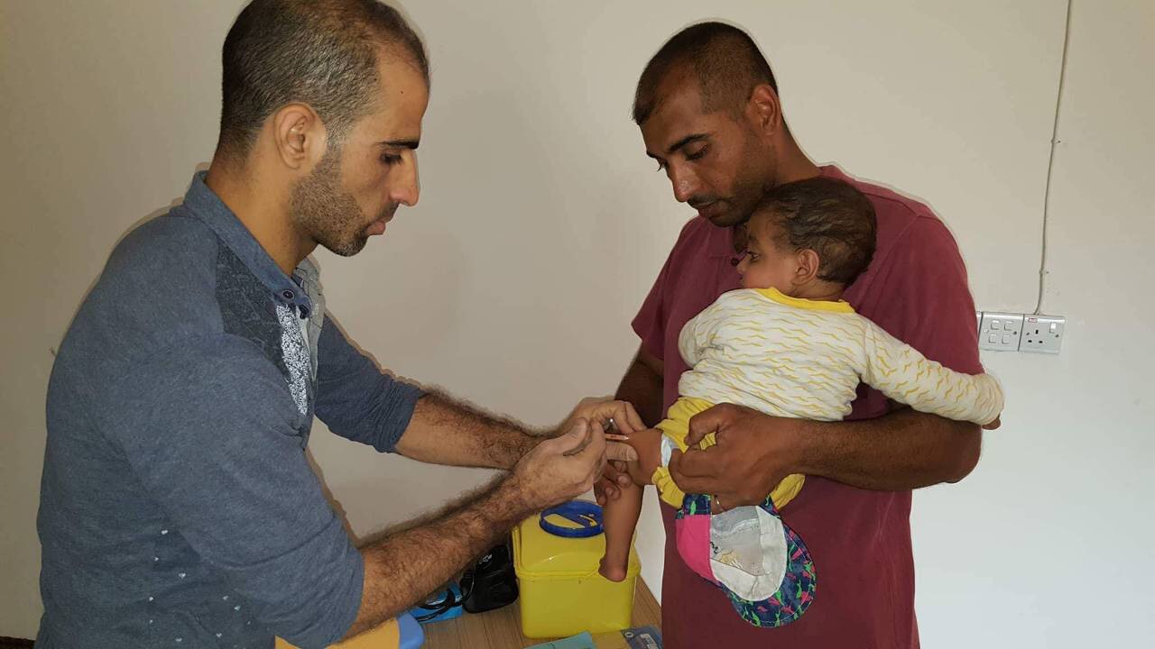  WHO-supported mobile medical team member vaccinates a child in Hawiija district