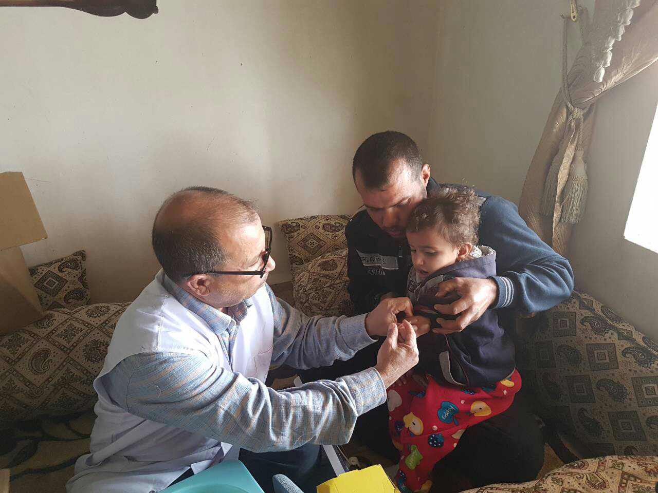 A child in Hawiija receives a measles vaccine from a mobile medical team member 