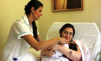 A woman in a hospital bed holds her newborn baby