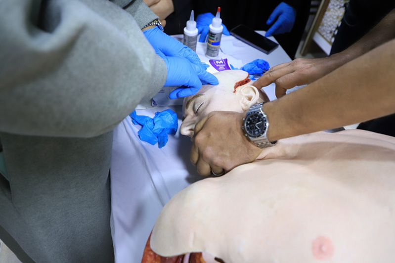 Participants practice wound management techniques on a medical mannequin during the Hostile Environment Surgical Training, focusing on real-life scenarios in conflict zones. Photo: WHO